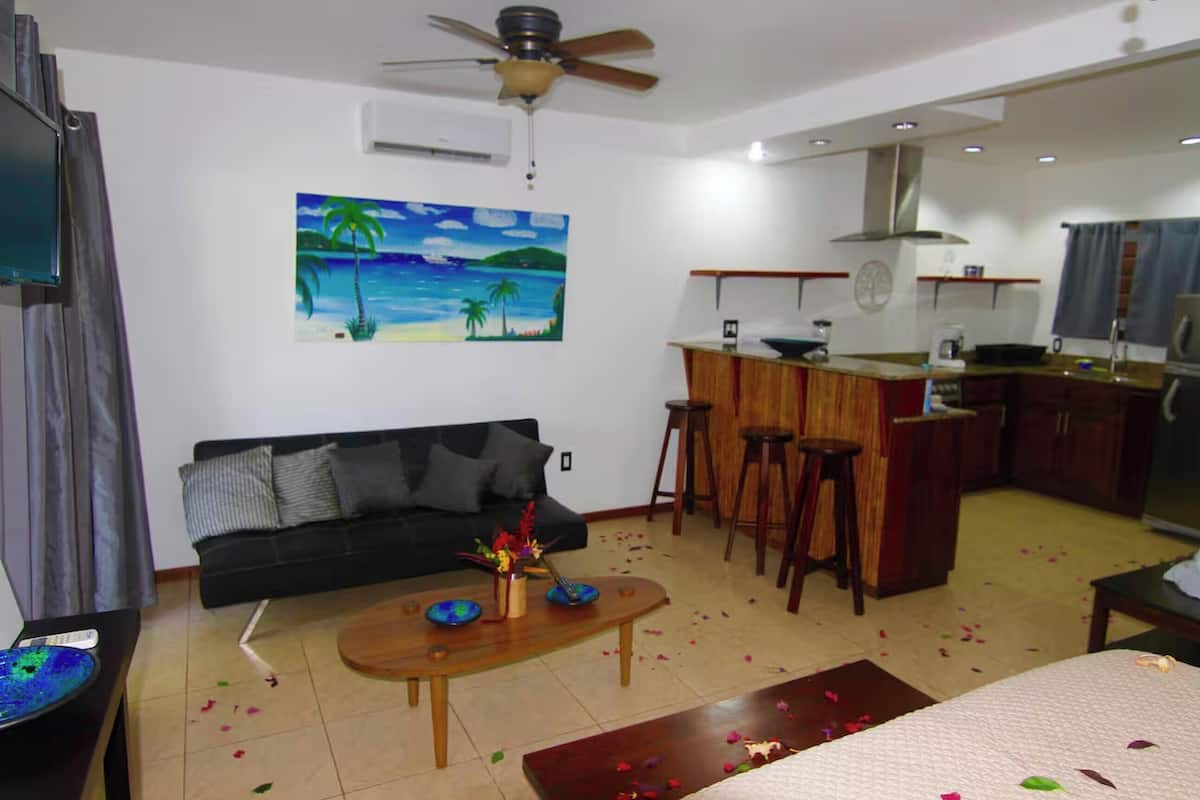 A living room with a sofa, coffee table, and painting of a beach scene.