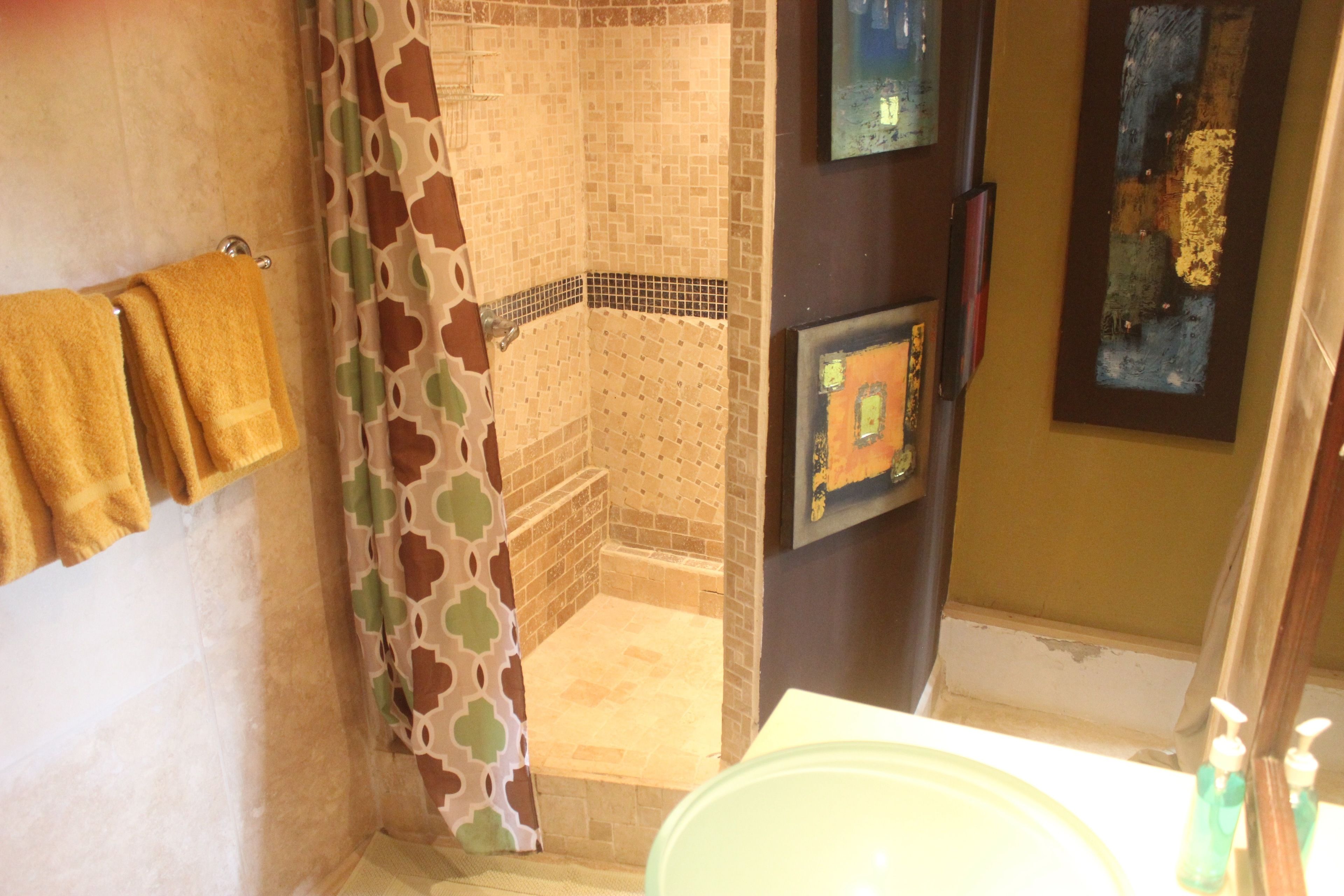 Une salle de bain avec une douche, un lavabo équipé de produits de toilette et un porte-serviettes.