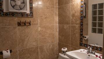 A bathroom with a toilet, sink, and mirror. There is a towel rack and a trash bin.
