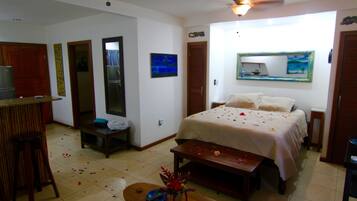 A hotel room with a bed, a desk, a chair, a small table, and a TV.