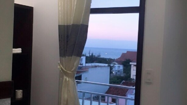 A balcony with a view of the sea, a curtain, and a door. - Khach San Yen Phu (Tuy Hoa)