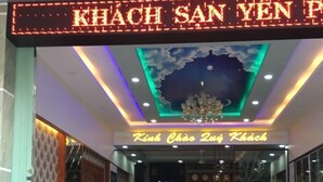A hotel entrance with a neon sign reading "KHACH SAN YEN PH", a chandelier, and two motorcycles parked outside. - Khach San Yen Phu (Tuy Hoa)