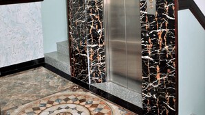 An elevator with a black and white marble wall, a metallic door, and a patterned floor. - Khach San Yen Phu (Tuy Hoa)