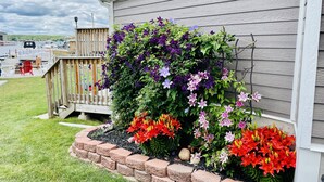 Ein Haus mit einem Blumenbeet und einer Holzterrasse.