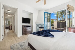 Un dormitorio con una cama grande, chimenea, televisor y vistas al exterior.