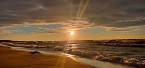 A beach with waves and a sunset.