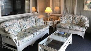 Une pièce chaleureuse avec deux canapés à motifs floraux, une petite table avec une lampe et une fenêtre avec des rideaux.