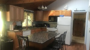 Une cuisine avec des meubles en bois, un plan de travail en granit, un réfrigérateur blanc et une cuisinière.