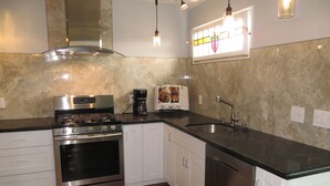 Una cocina moderna con electrodomésticos de acero inoxidable, armarios blancos y una encimera negra.