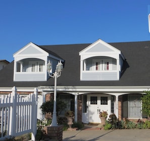 A two-story house with a front porch, a picket fence, and a street lamp.