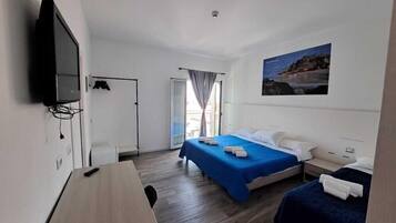 A hotel room with a bed, a desk, a chair, a television, and a window with curtains.