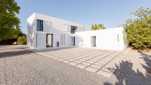 A modern white house with a paved driveway and a gravel area in front. - Modern Villa with pool close to IBIZA. (IBIZA)