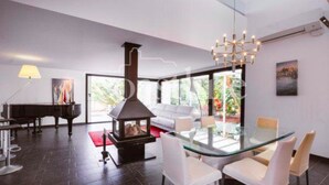 A modern living room with a glass dining table, white chairs, a piano, and a fireplace. - Modern Villa with pool close to IBIZA. (IBIZA)