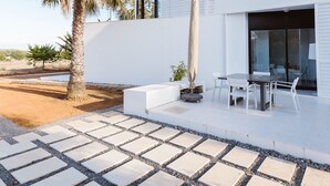A modern house with a white exterior, a paved patio with stone tiles, a palm tree, and a dining area with outdoor furniture. - Modern Villa with pool close to IBIZA. (IBIZA)