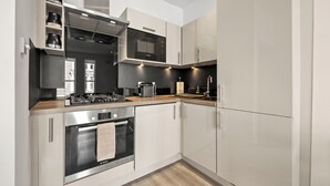 A modern kitchen with stainless steel appliances, white cabinetry, and a wooden countertop. - Comfy Modern 2-Bed Notting Hill Portobello Apt (London)