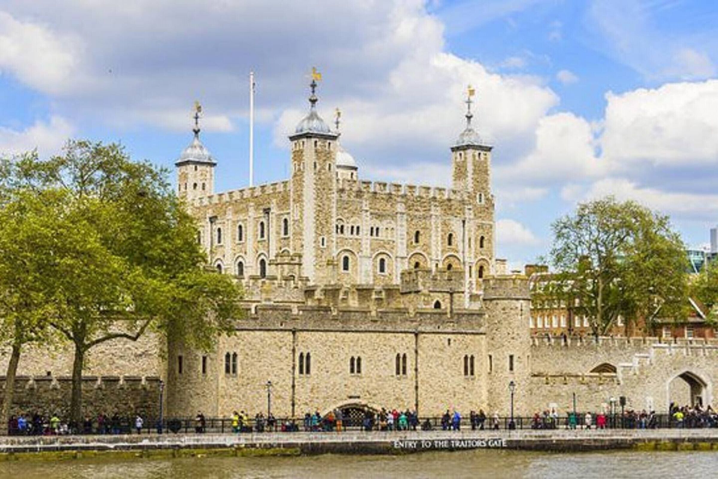 A historic stone building with multiple towers and a large crowd gathered in front.