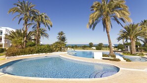 A swimming pool surrounded by palm trees and a clear blue sky. - 112 Alberca 8-5 (Denia)