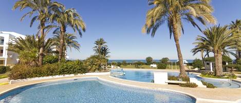 A swimming pool surrounded by palm trees and a clear blue sky.