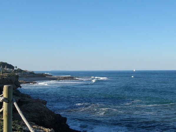 A coastal view with a wooden post and rope barrier, a clear sky, and a distant sailboat. - 112 Alberca 8-5 (Denia)