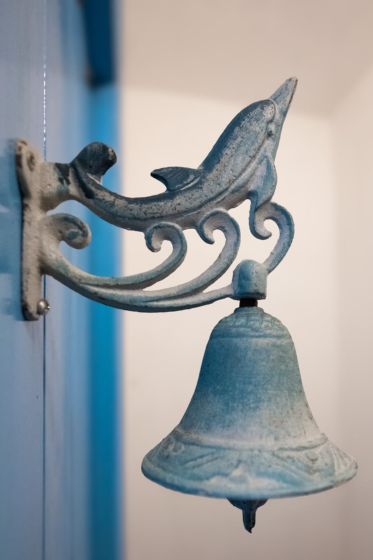 A metal bell with a decorative finial attached to a wall.
