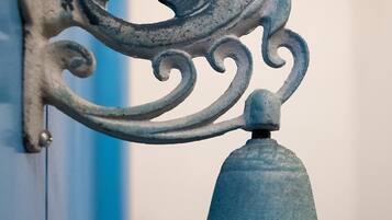 A metal bell with a decorative finial attached to a wall.