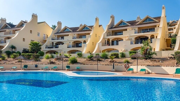 Et resort med swimmingpool, flere balkoner og et ørkenlandskab.