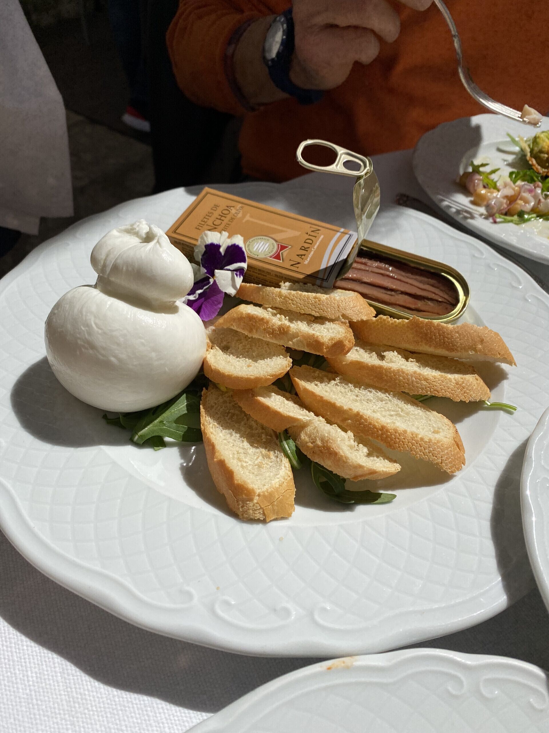 Un plato con un postre que incluye una bola de helado, rebanadas de pan y un pequeño recipiente de confitura.