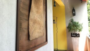 A wall-mounted wooden frame with a woven textile, a wall-mounted lantern, and a sign indicating a cafe. - Blue Pillars Kandy (Kandy)