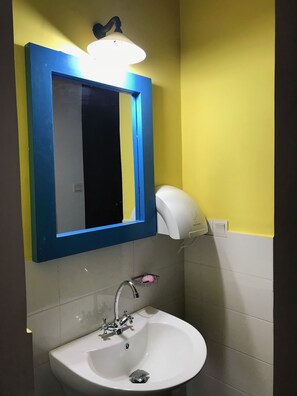 A bathroom with a white sink, a mirror with a blue frame, and a hand dryer. - Blue Pillars Kandy (Kandy)
