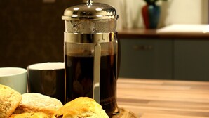 Una macchina per caffè, un piatto con dei biscotti e una tazza su un vassoio di legno.