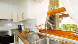 Cucina con mobili bianchi, lavello in acciaio inossidabile e piano di lavoro in legno.