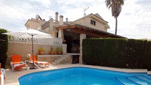 Una piscina con un mosaico a forma di stella, circondata da sdraio e una palma.