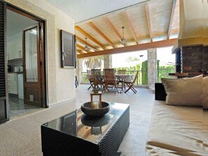 A spacious living area with a glass coffee table, a sofa, and a dining set. A kitchen is visible in the background. - Holiday Villa with pool in Playa de Muro (Muro - Platja Muro)