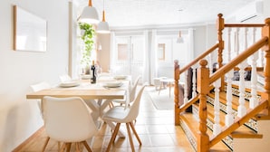 A dining area with a wooden table, white chairs, and hanging pendant lights. - House of 200 square meters in the historic center of Javea (Jávea)