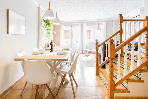 A dining area with a wooden table, white chairs, and hanging pendant lights. - House of 200 square meters in the historic center of Javea (Jávea)