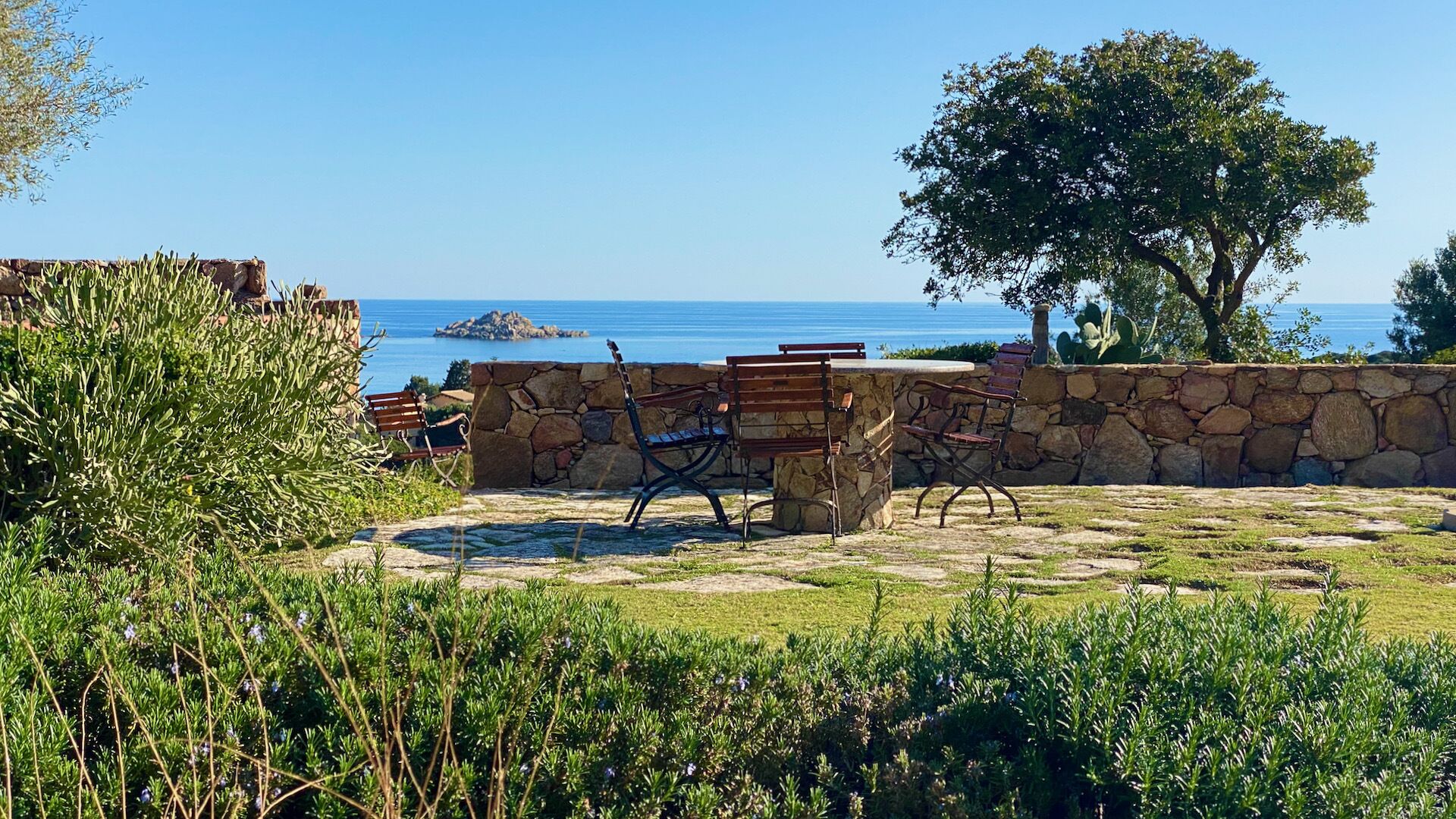 Un espace extérieur aménagé avec des murs en pierre et une vue sur la mer.