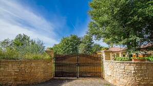 A gated entrance with a stone wall and a metal gate.