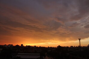 Une vue sur les gratte-ciel d’une ville au coucher du soleil, avec une tour de communication bien visible.