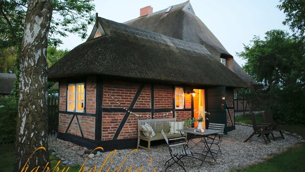 A traditional thatched-roof cottage with a brick exterior, a bench, and a table set outdoors. - Kl. Reetkate f. 2 pers. / WLAN / sauna / garden / a few minutes to the beach (Behrensdorf)
