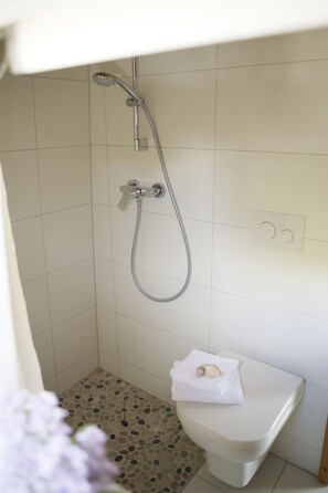Ein Badezimmer mit Dusche, Toilette und Fliesenboden.