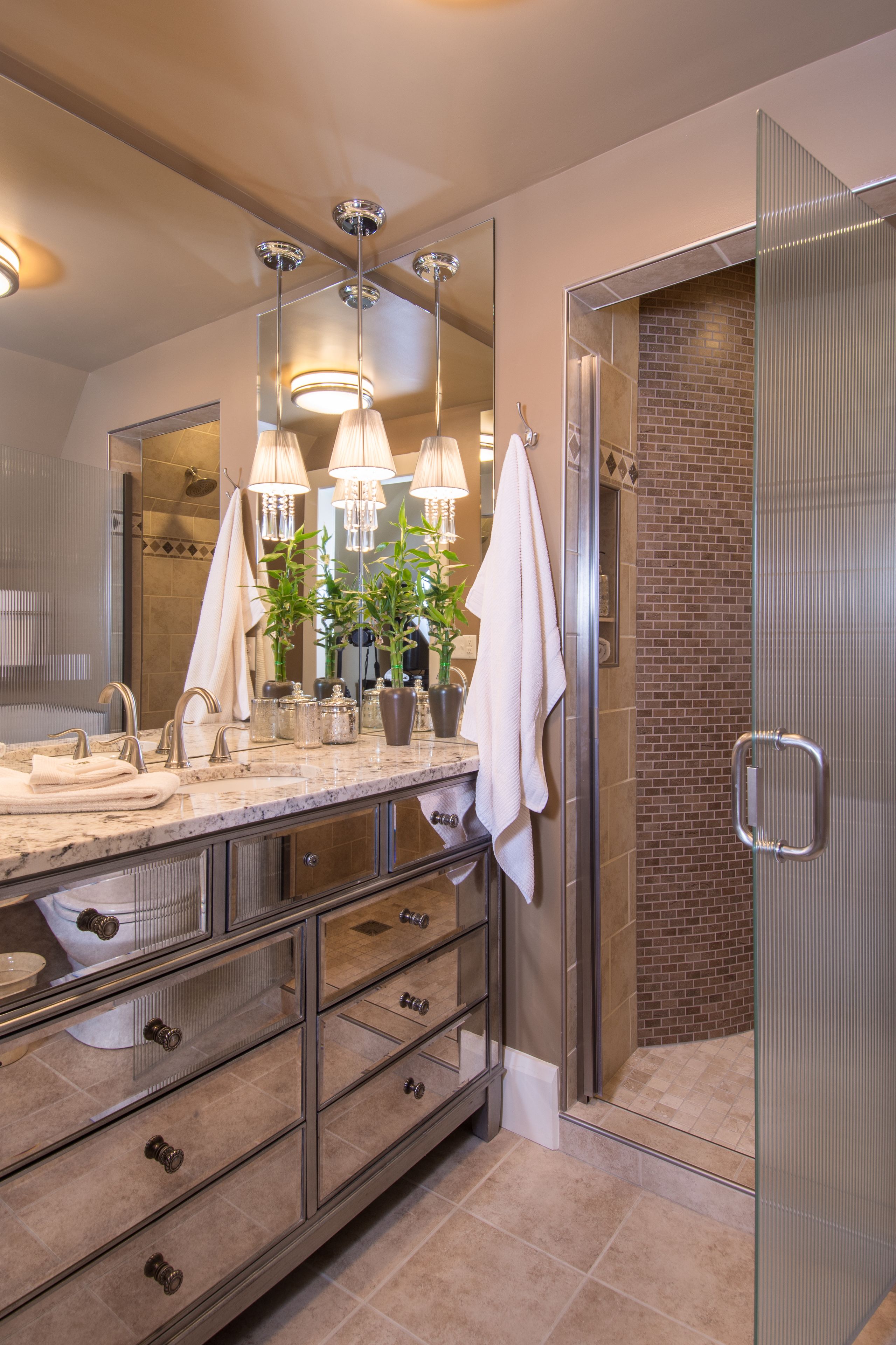 A modern bathroom with a large mirror, multiple light fixtures, and a walk-in shower.