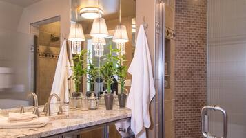 A modern bathroom with a large mirror, multiple light fixtures, and a walk-in shower.