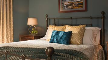 A neatly made bed with patterned bedding, a bedside table with a lamp, and a framed picture on the wall.