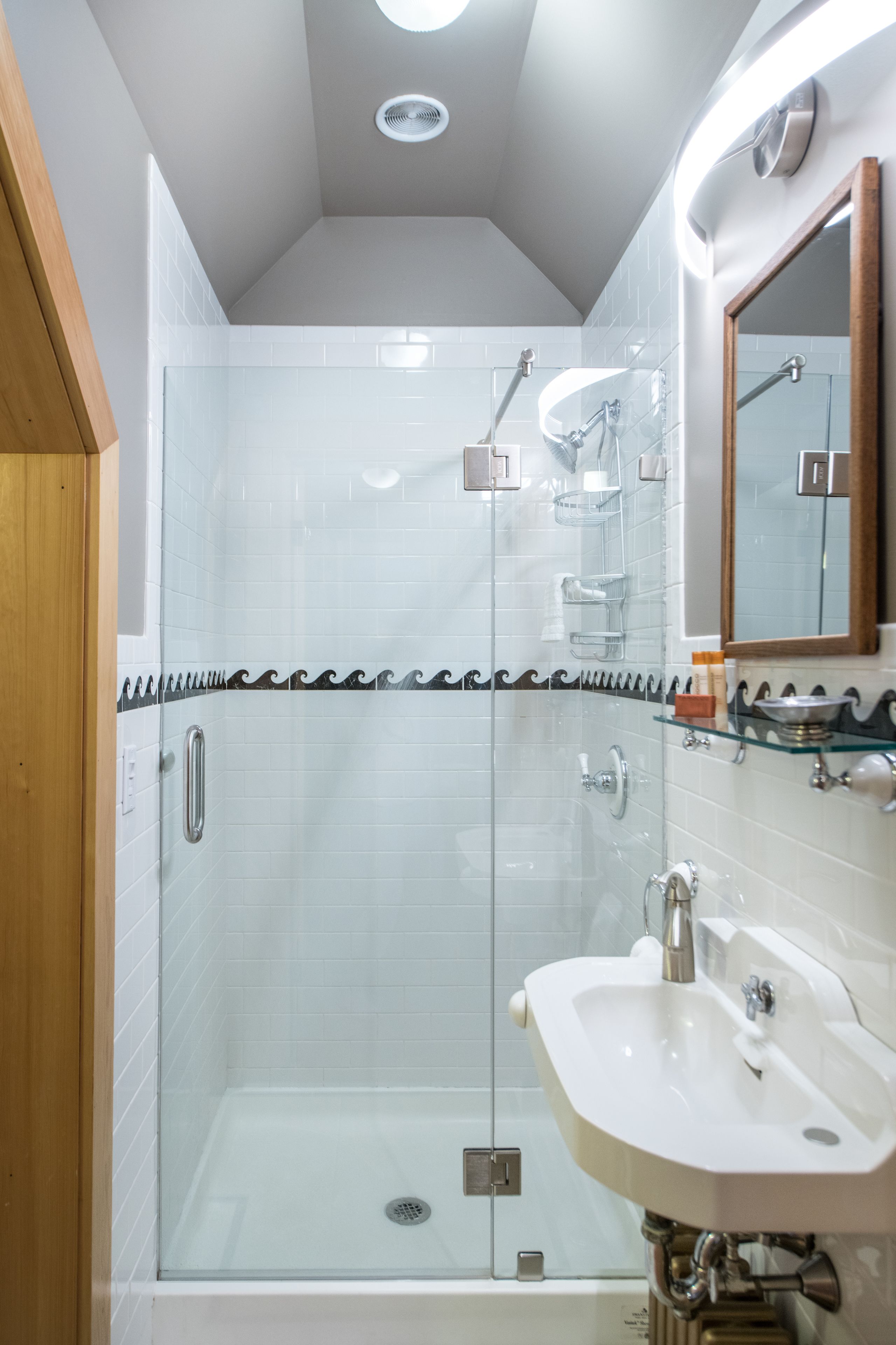 A modern bathroom with a glass-enclosed shower, a white sink, and a mirror above it.