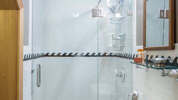 A modern bathroom with a glass-enclosed shower, a white sink, and a mirror above it.
