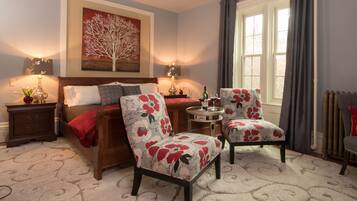 Une chambre à coucher avec un lit, deux chaises, une table de chevet, une lampe et un tableau au mur.