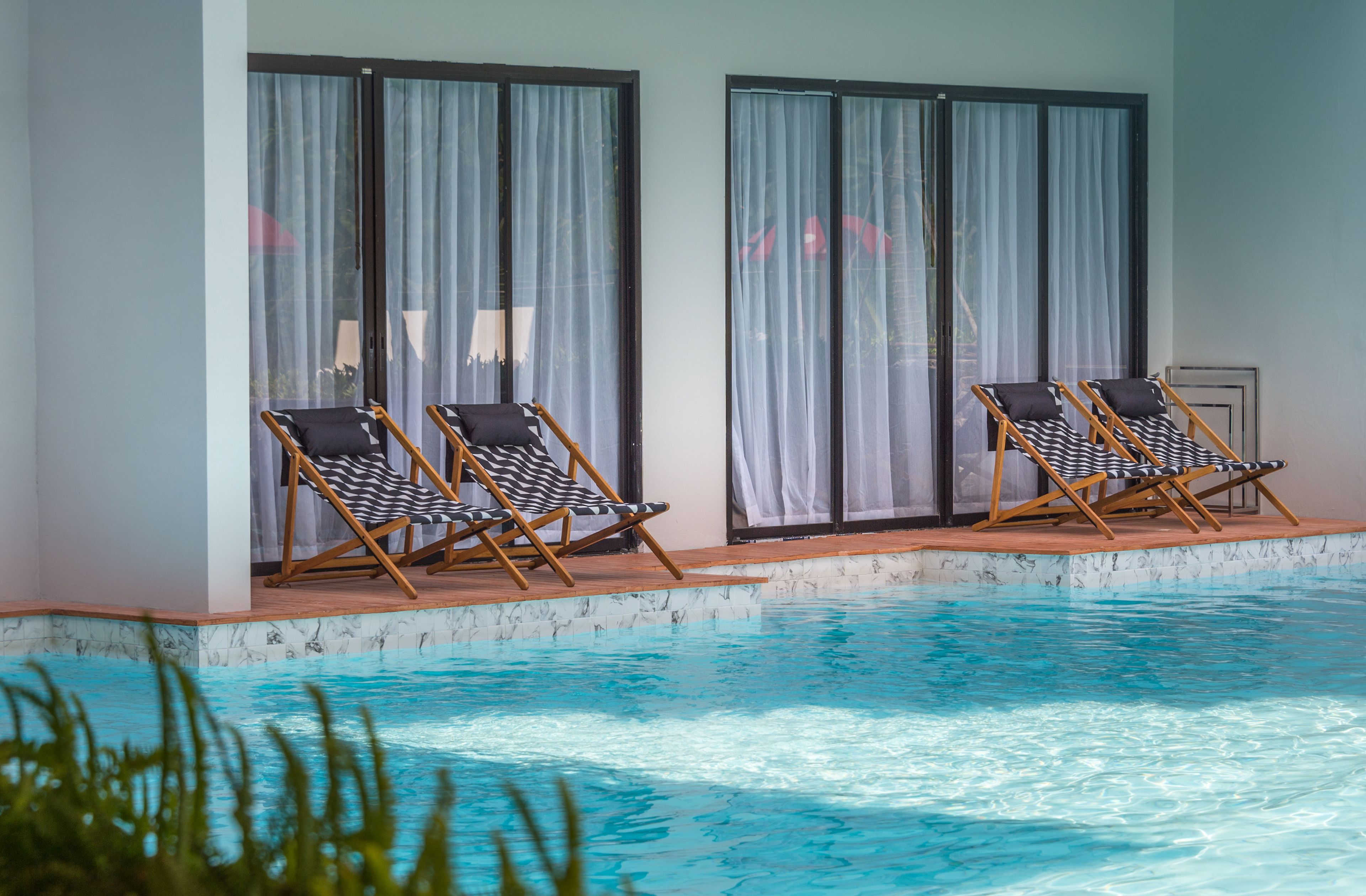 A poolside area with two lounge chairs and a tiled deck.