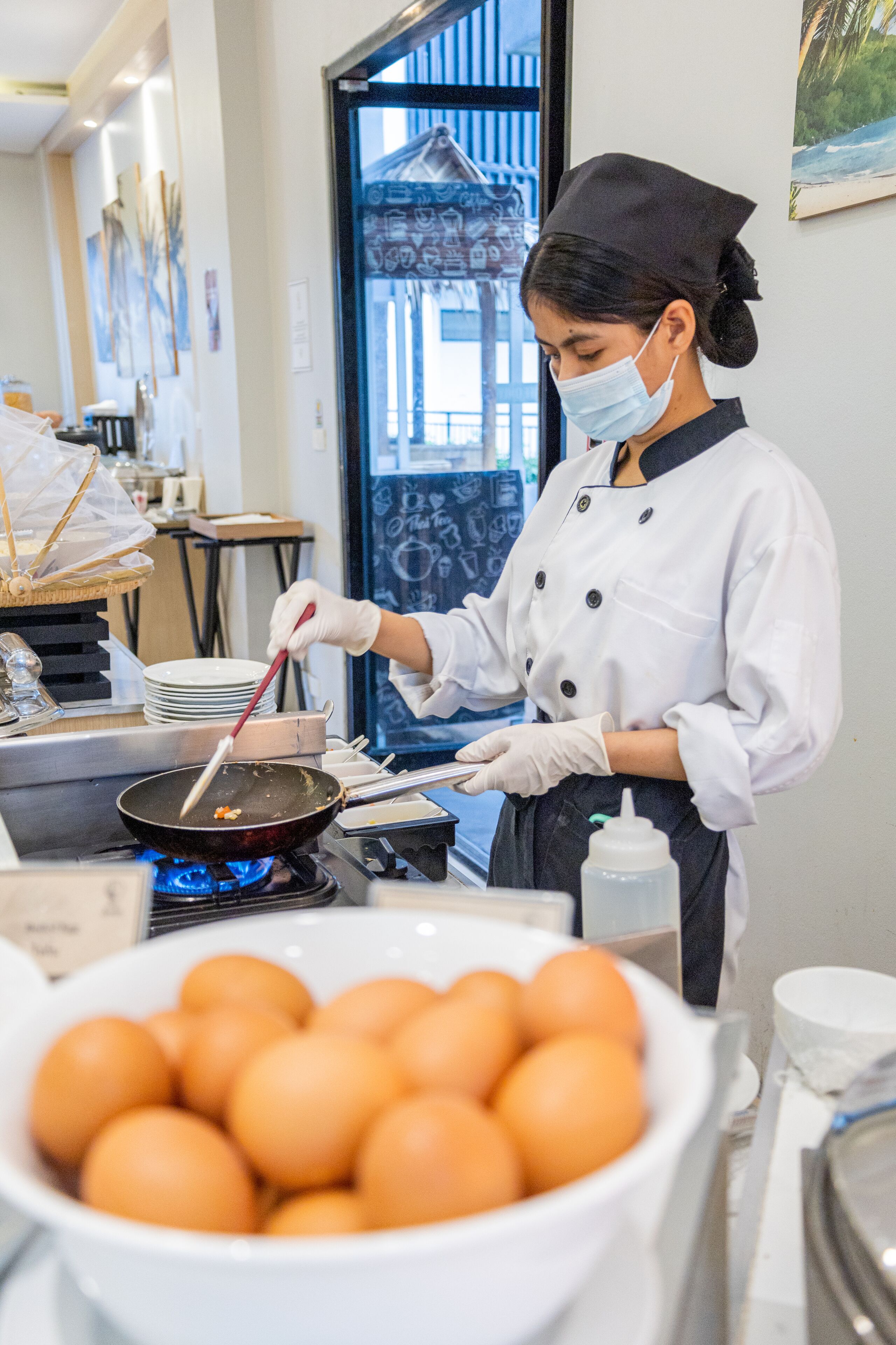 A chef cooking in a kitchen with a bowl of eggs in the foreground.