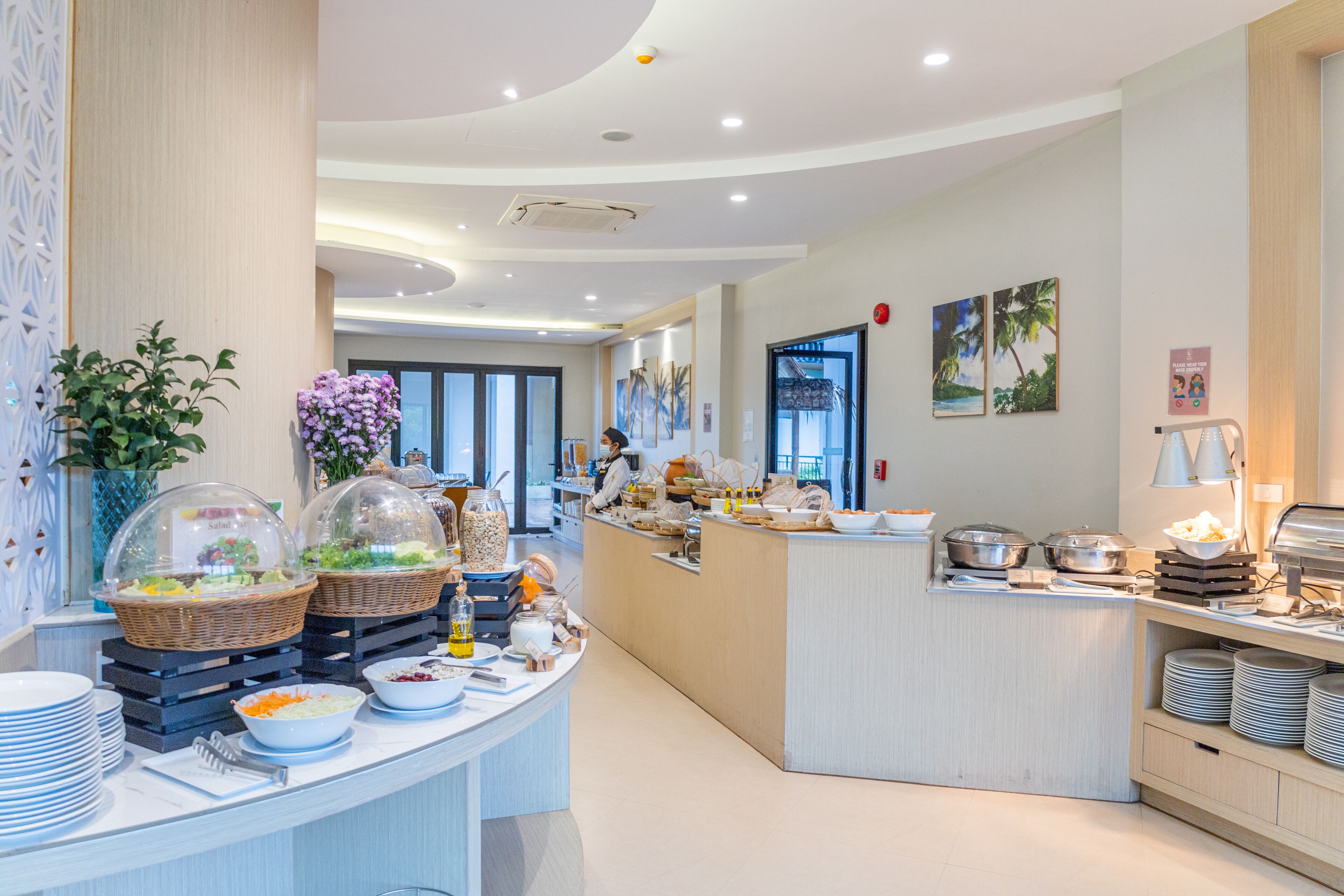 Un moderno vestíbulo de hotel con una zona de buffet que ofrece diversas opciones de comida y elementos decorativos.