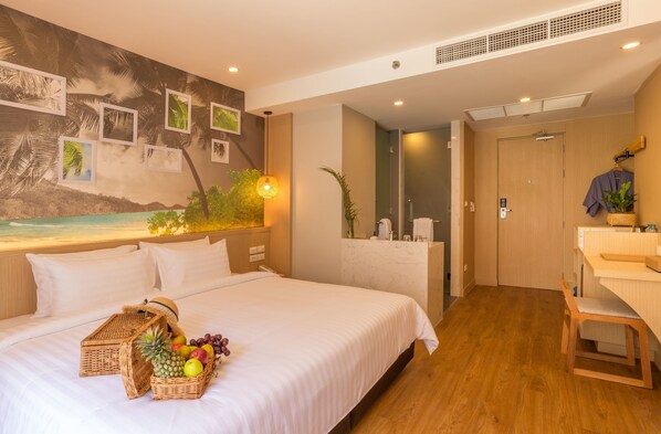 A hotel room with a bed, a desk, a bathroom, and a wall with framed pictures. - Sea Seeker Krabi Resort (Krabi)